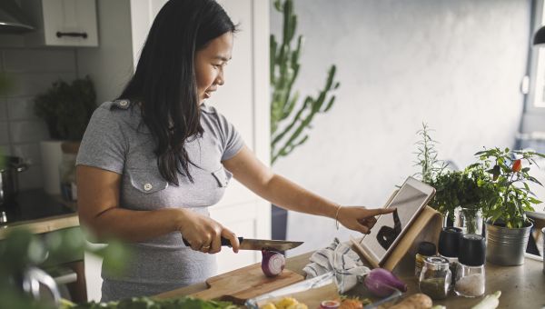 Young Asian woman in kitchen cooking with ipad