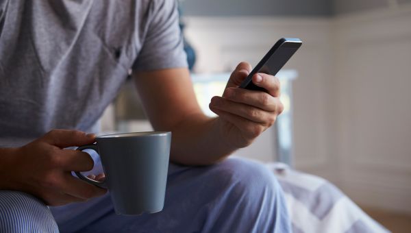 Man with a mug using a smartphone