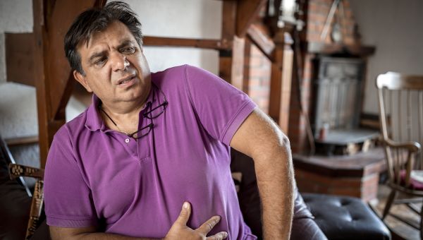 Older man in purple shirt with stomach pain