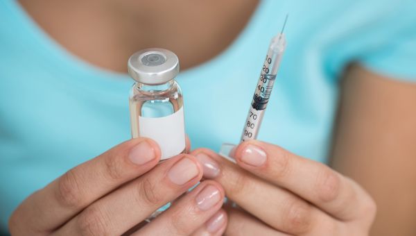 Woman holds insulin vial and needle.