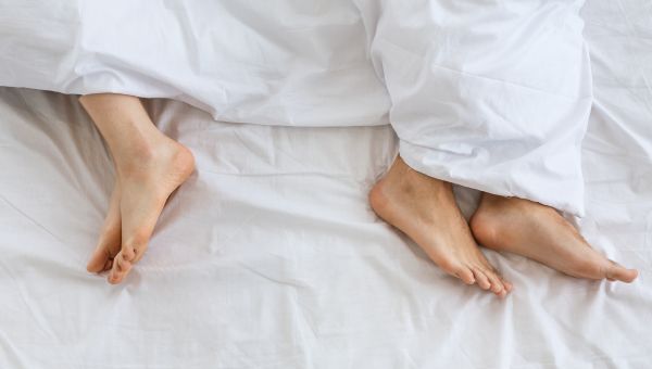 woman and man's feet covered by a sheet in a bed