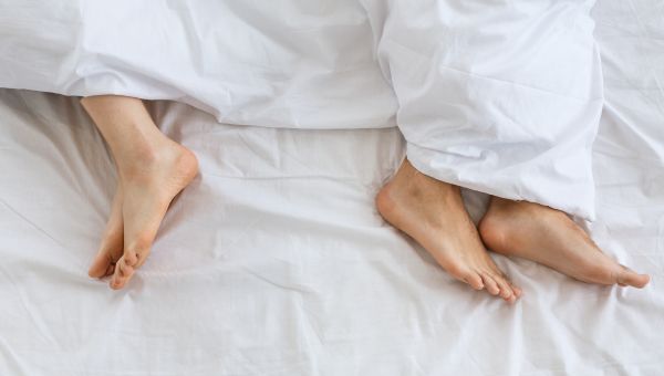 two people's feet covered by a sheet in a bed