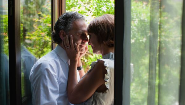 middle aged white couple embraces in glass door