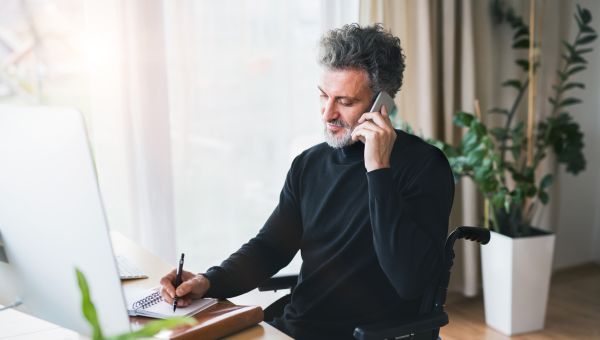 man in wheelchair on the phone at desk