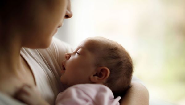 New parent holding their newborn before breastfeeding.