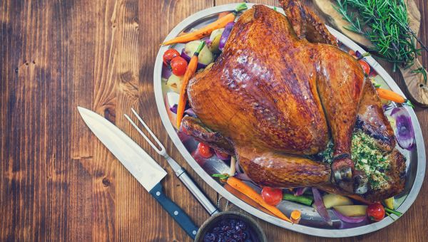 A healthy, well-baked turkey on a bed of vegetables.