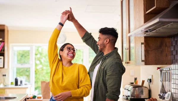 a young BIPOC heterosexual couple dance together in their kitchen 