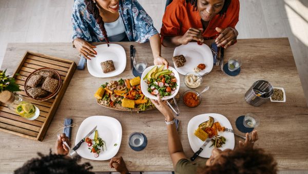 Four black women sitting around a table and enjoying a healthy meal together