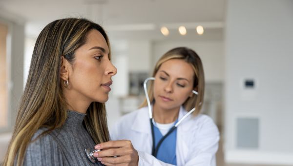 doctor using stethoscope on female patient 