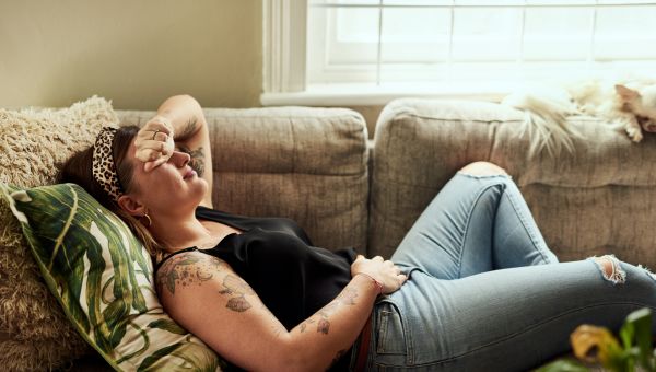 a woman in discomfort lies on her couch
