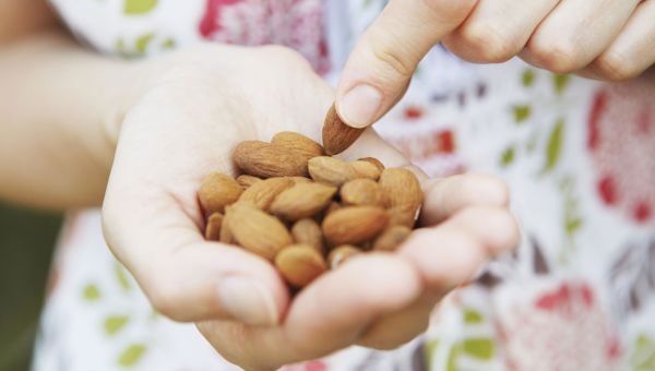 A hand filled with almonds, which is a paleo-friendly snack.