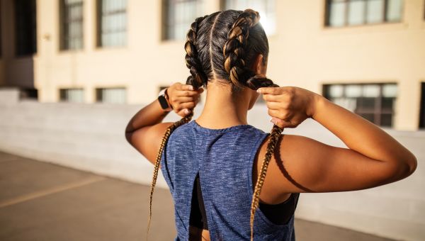 young person standing with back to camera, and holding a braid in each hand