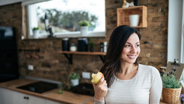 woman happily eating an apple indoors