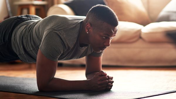 young black man doing a plank indoors
