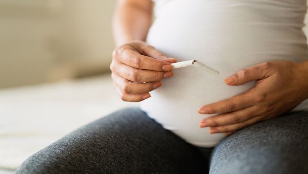 Up close image of a pregnant person breaking a cigarette in half