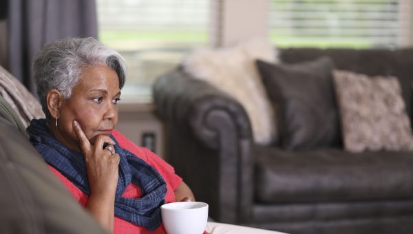 older woman looking contemplative while sipping cup of tea