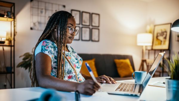 woman studying and taking notes from computer at home