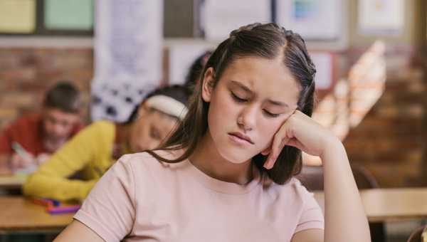 Preteen girl with ADHD in classroom looking frustrated