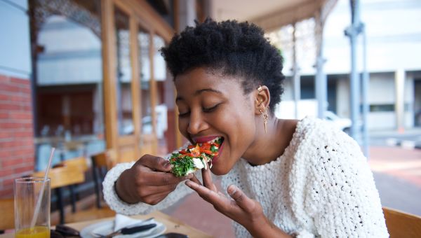 bright cheerful woman eats a vegetarian meal at a cafe