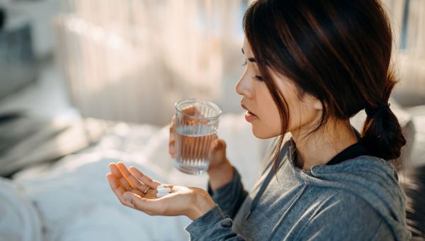 woman taking Imodium pills before a meal to prevent diarrhea