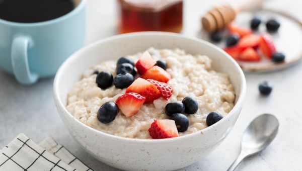 Oatmeal porridge with berries, honey and cup of coffee