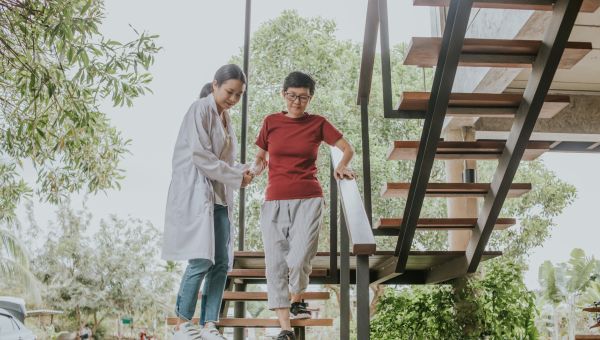 senior asian woman being helped down the stairs