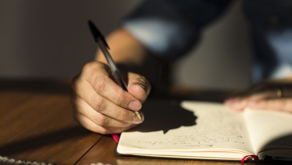 man writing in journal