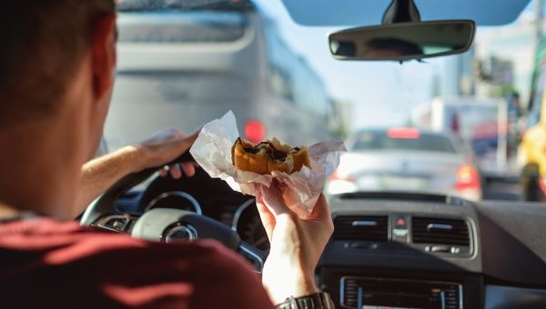 man eating burger in car
