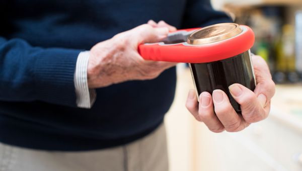 senior man using a can opener to open jar lid