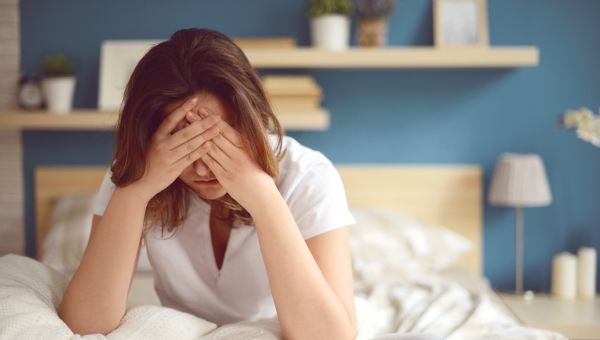 sad woman head in hands in bed