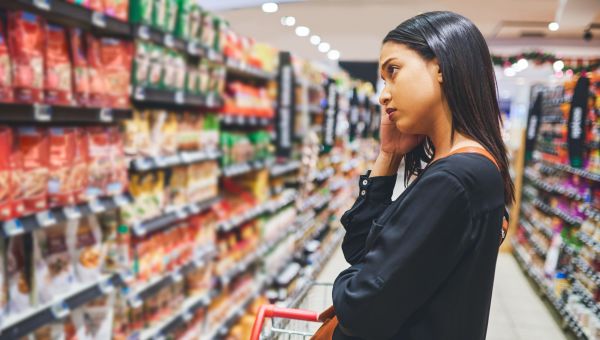 Young sad woman shopping in grocery store