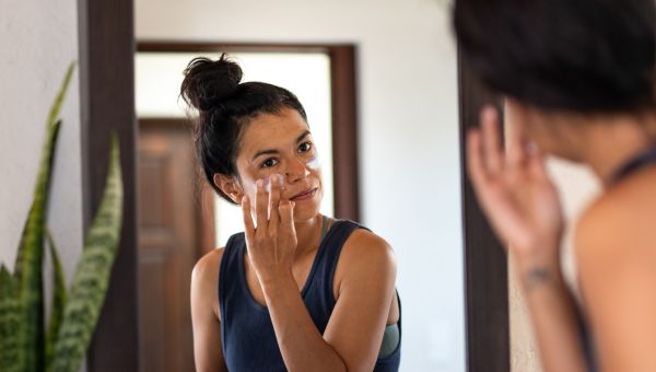 woman in bathroom applying sunscreen to face