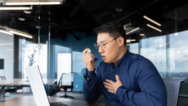 man with asthma using inhaler in office