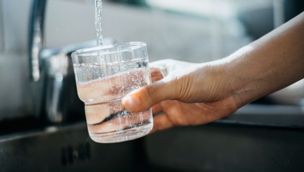 man's hand filling glass of water from faucet