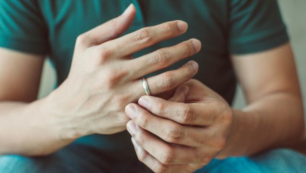 Someone taking gold wedding ring off their finger