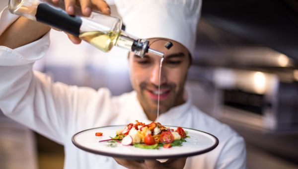 chef putting oil on a salad