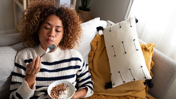 woman eats bowl of nuts, berries, and flaxseed