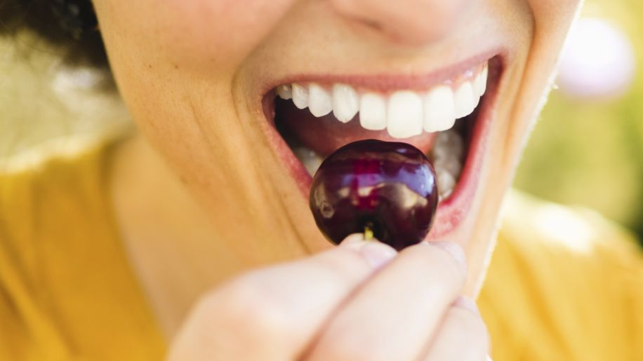 woman biting into cherry