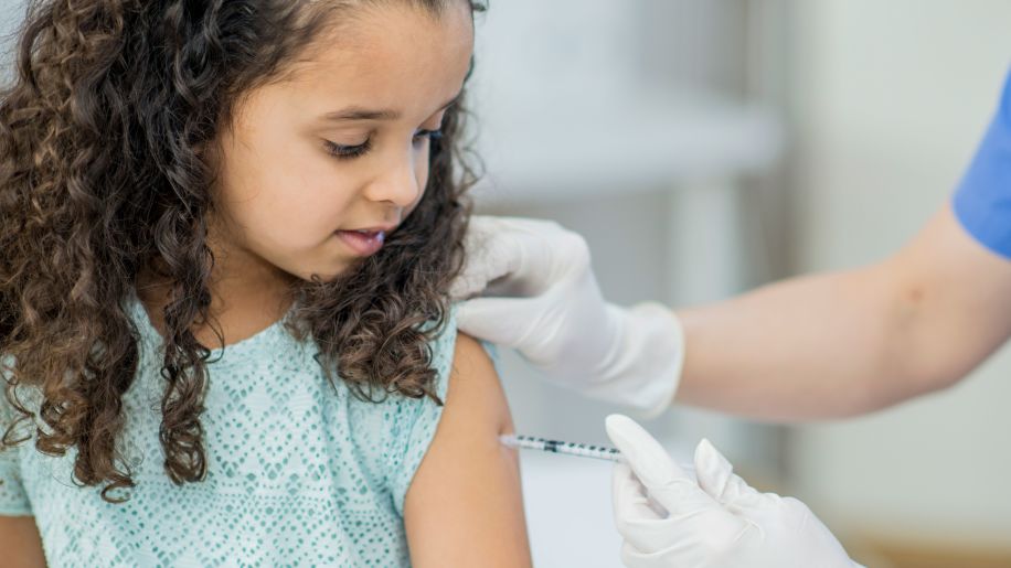 Nurse administering vaccine to a young girl