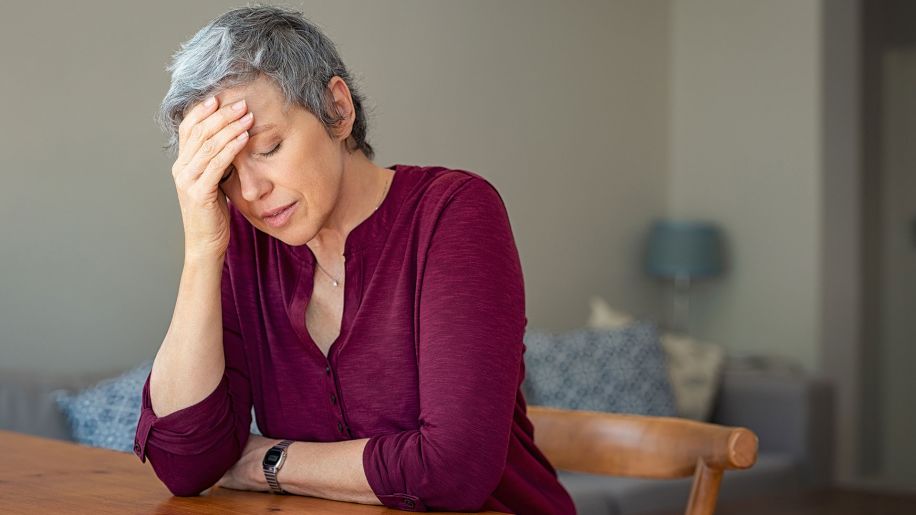 Older woman with a headache massaging her brow.