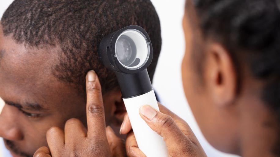 Dermatologist inspecting patient's scalp for skin cancer