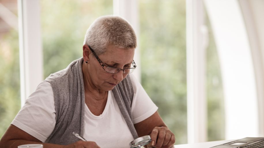 woman using magnifying glass to read