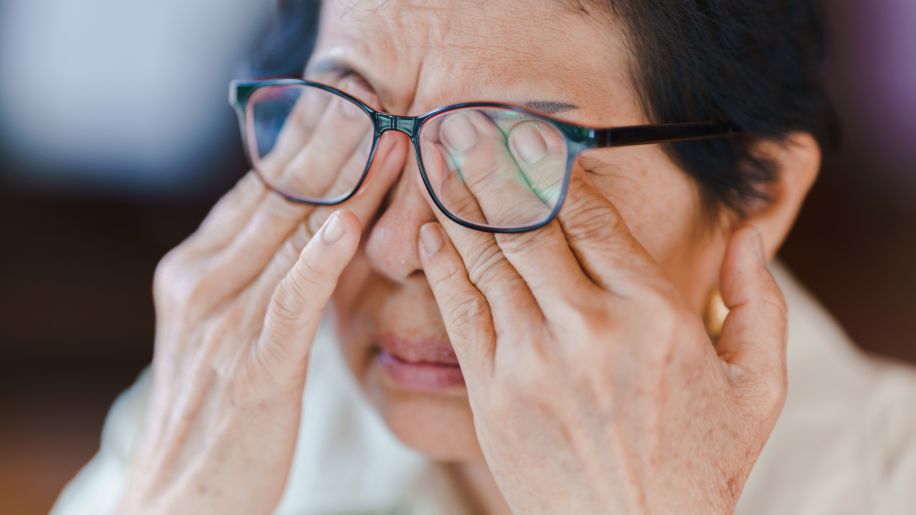 senior woman rubbing her eyes under glasses
