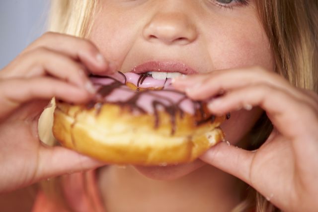 Close Up Of Girl Eating Iced Donut