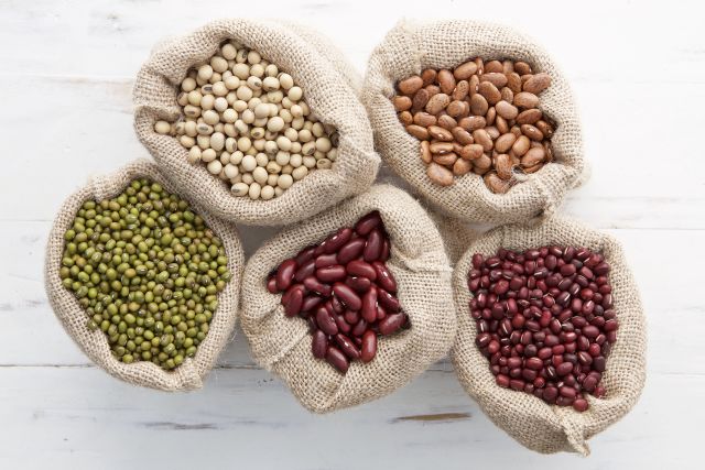 Assortment of beans and lentils in hemp sack on wooden background. green bean, groundnut, soybean, red kidney bean , black bean ,red bean and brown pinto beans