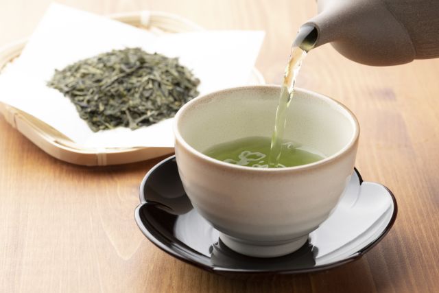 Close-up of a cup of green tea in hands of a businessman