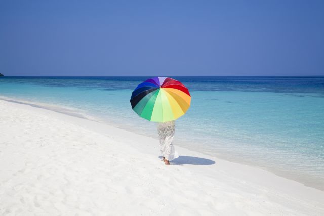 woman walking on beach with umbrella