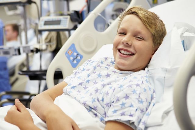 Young Male Patient In Hospital Bed Smiling At Camera