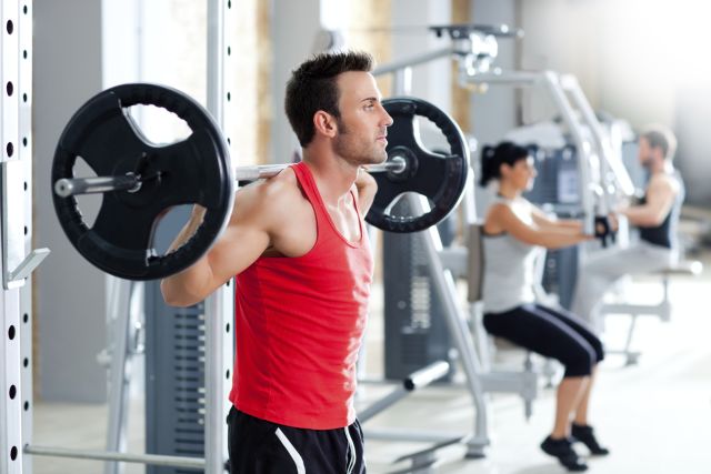 Muscular man working out in a gym gets ready for strength training as a way to reduce appetite and build muscle.