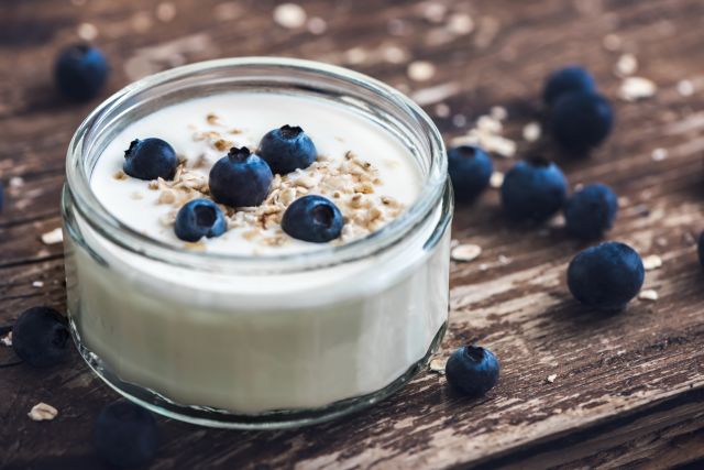 Serving of Yogurt with Whole Fresh Blueberries and Oatmeal on Old Rustic Wooden Table. Closeup Detail.